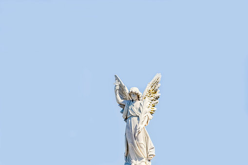 Old statue of angle with cross in cemetery build in 1877 Sydney Australia, blue sky background with copy space, horizontal composition