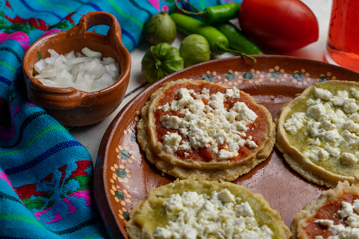 Traditional mexican picaditas with sauce and fresh cheese on blue background