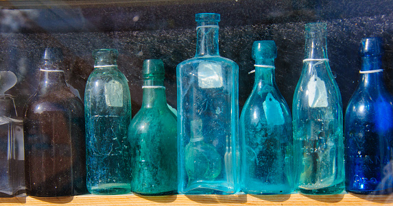 Still life at a lost place. Ancient glass bottles of various sizes on a shelf in an abandoned wooden shed.