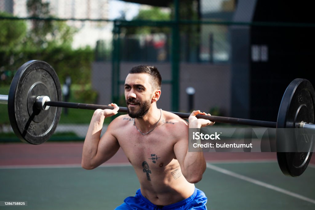 man working bodybuilding by lifting weights barbell Deltoid Stock Photo