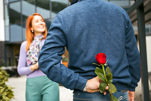 Young woman receiving beautiful bouquet of roses from her boyfriend indoors. Valentine's day celebration