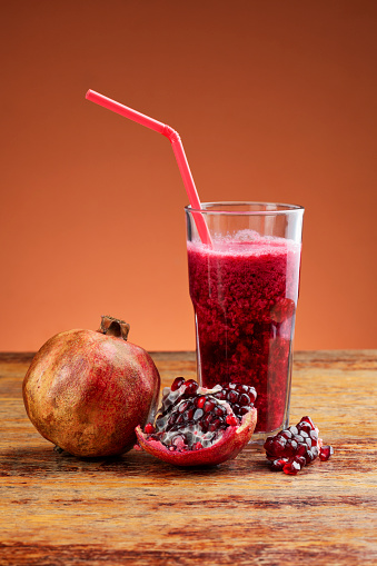Pomegranate and juice of pomegranate photographed on wooden table
