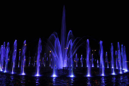 fountain water stream jets in a ring at dark night blue lights
