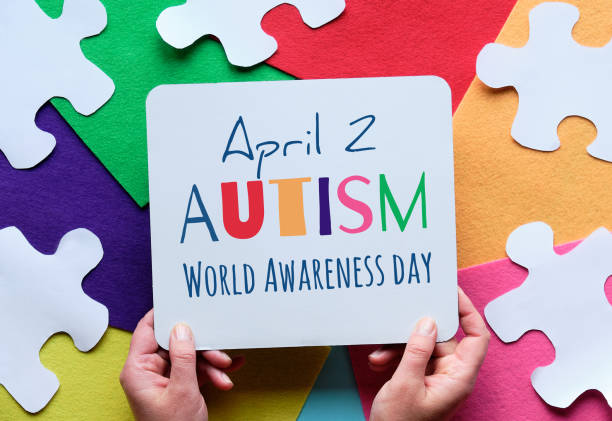 Hands hold board. with text April 2 Autism World Awareness day. Puzzle, layered felt background