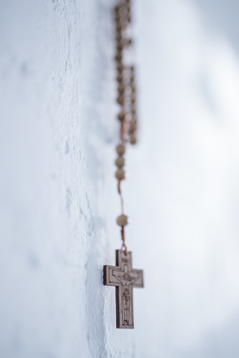 Rosary, holy cross. White wall in background. Krakow in Poland. No people. Close shot.