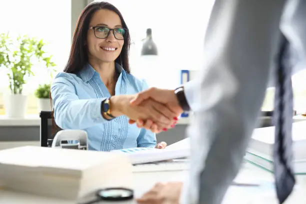 Photo of Businesswoman smiles and shakes hands with her partner