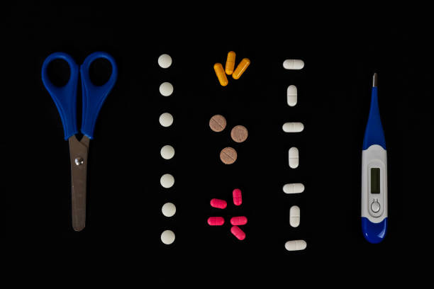 Different medicine pills, tablets and capsules, thermometer and scissors on a dark background. Pharmaceutical picture. Nice flatlay. Health care. Top view. Space for text. Copy space. New image