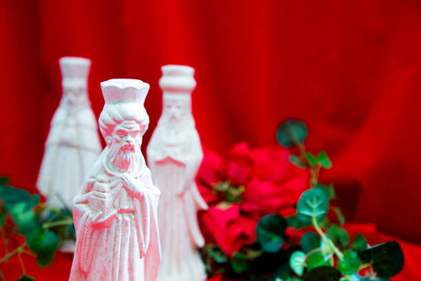Three Wise Men, Kings, bringing gifts to the Baby Jesus.  Today, wise men still seek Him and celebrate His birth.Red Background with poinsettia and greenery..