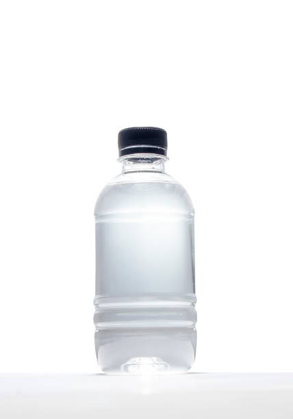 Black screw cap plastic water bottle set on a white table and a white background