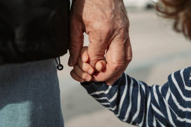 großvater hält seinen enkel an der hand - grandson stock-fotos und bilder