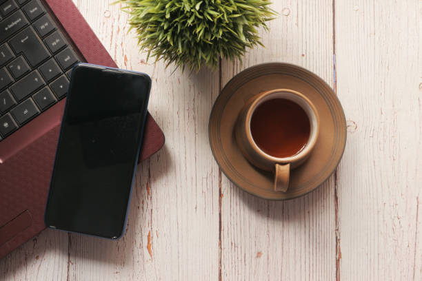 istock smart phone with empty screen, laptop on wooden background 1286785891