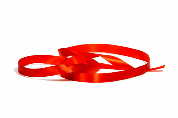 istock Delicate red satin wavy ribbon on a white isolated background, with a soft shadow.Design concept for new year or Christmas holidays. Close-up, selective focus. 1286792168