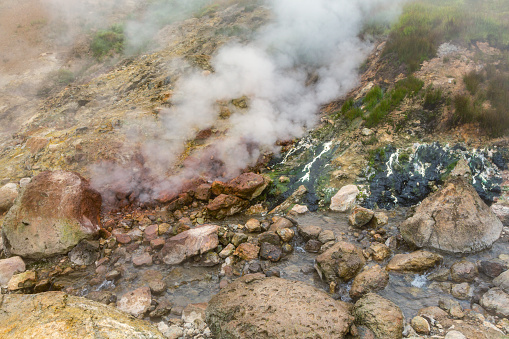 Thrilling view of volcanic landscape, aggressive hot spring, eruption fumarole, gas-steam activity in crater of active volcano. Scenery mountain, travel destinations for active vacation and hiking.