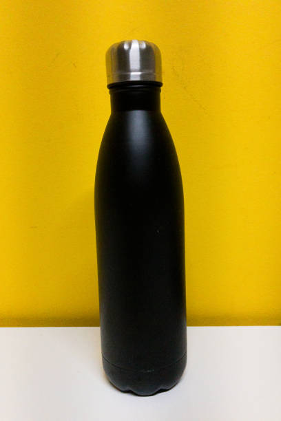 istock Black aluminum bottle on yellow background and white table 1286798374