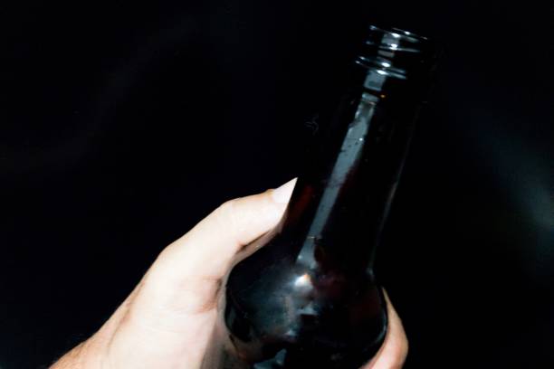 istock Hand holding beer bottle on black background 1286799190