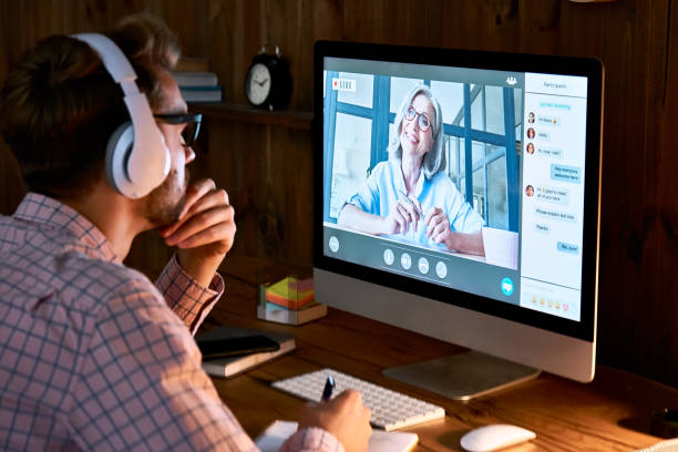 estudiante masculino que lleva auriculares que toman formación en curso en línea, ver seminarios web, seminarios remotos de clase universitaria, aprendizaje virtual con profesor web de distancia social, tutor o entrenador en la pantalla de la computadora - conference business meeting training fotografías e imágenes de stock