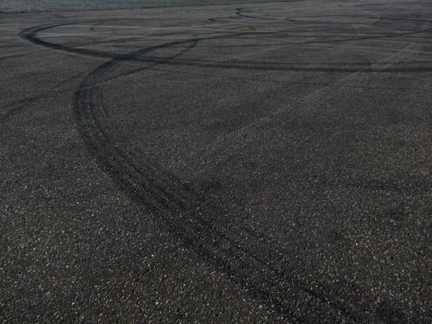 Traces of car tires from drift on grey asphalt - background The concept of street racing and drifting on grey asphalt - car tire marks on the asphalt Warm Mix Asphalt Additives stock pictures, royalty-free photos & images