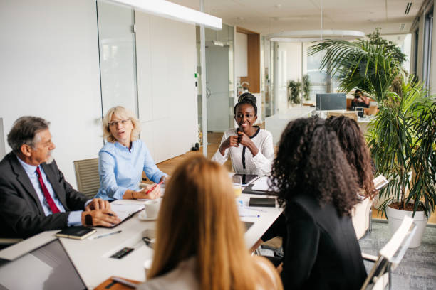 Indoor photo business people on a meeting Indoor photo of multi ethnic business people having a strategy meeting in the board room. Colleagues are discussing different fields. Horizontal photo with copy space. Bright atmosphere in a modern office space with lots of grenery. formal businesswear stock pictures, royalty-free photos & images