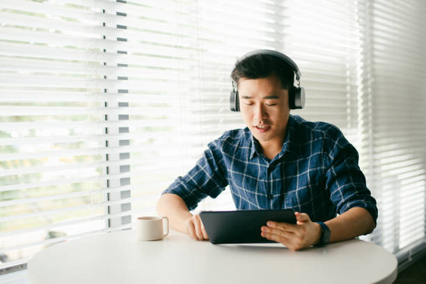 istock An Asian man using wireless headphones with a digital tablet in living room 1286820601