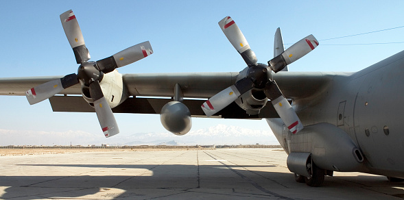 The wing and 2 engines of an unidentified military C-130 Hercules Cargo transport aircraft