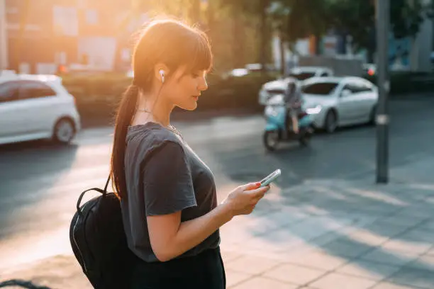 Urban women: a portrait of a pretty young woman wearing grey and black, looking at her smartphone.