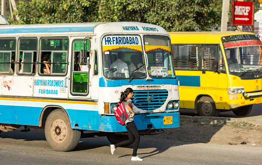 Faridabad, Haryana/ India - September 28, 2019: Young Indian girl running to board the Haryana Roadways bus in Faridabad, India