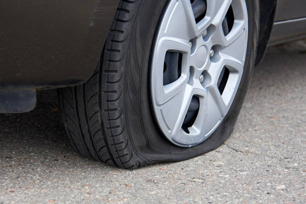 Flat tire of a car, trouble on the road. Flat tire of a passenger car, trouble on the road. flat tire stock pictures, royalty-free photos & images