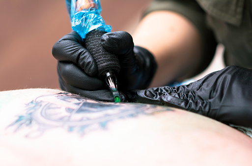 Close up tattooing process, Woman master getting tattoo in studio