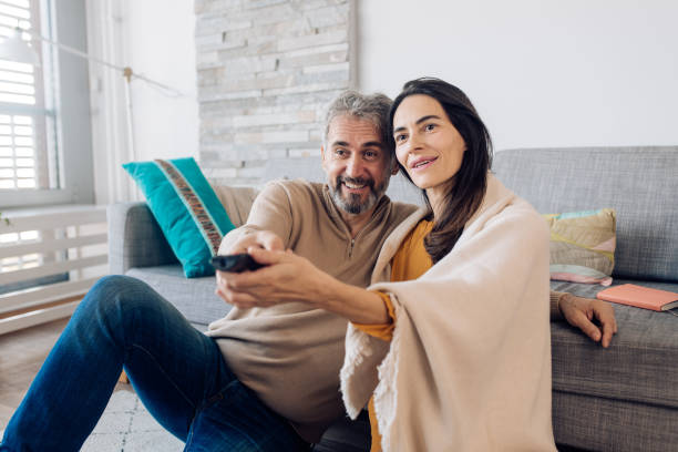 istock Happy couple watching TV at home 1286835048