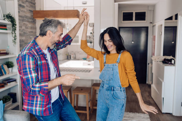 Happy mature couple making their own dancing party at home Happy mature couple dancing and enjoying together at home. middle aged couple dancing stock pictures, royalty-free photos & images