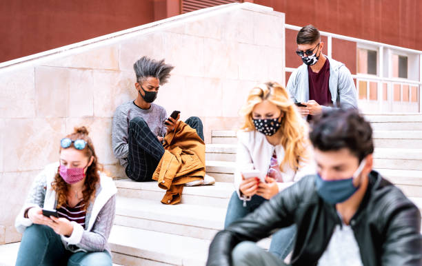 istock Urban milenial students using smart phones with face mask on Covid second wave - Serious guys and girl watching video on smartphone - College friends busy at university break - Bright contrast filter 1286835821
