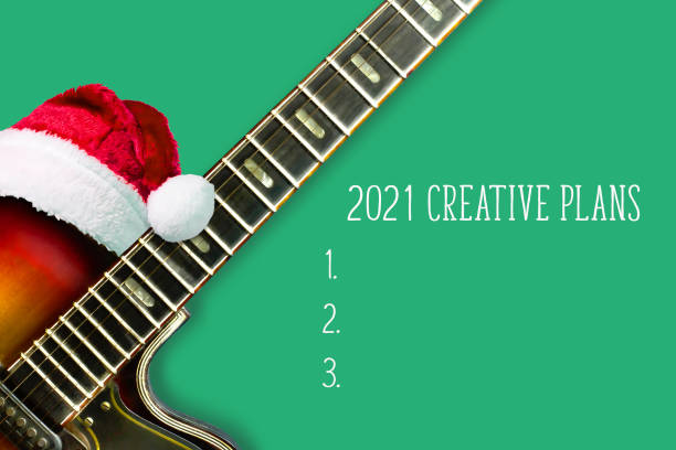 istock 2021 Creative plans. Electro guitar in a Santa hat, on a green background. Concept of creative plans for the next year. Training. 1286838818