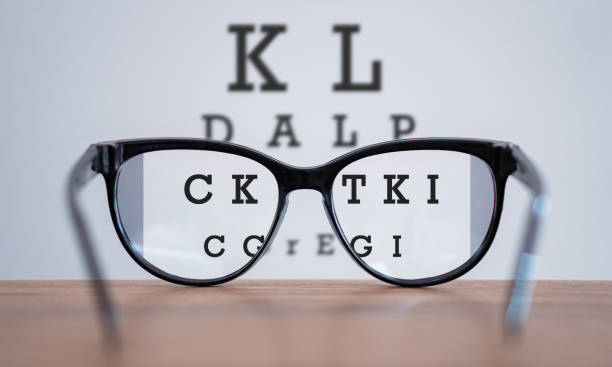 brillen während optometrischen untersuchungskonzept mit holztisch, gläser auf tisch und alphabet buchstaben frontansicht. - sehen stock-fotos und bilder