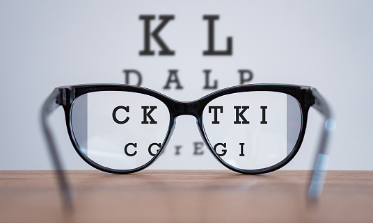 Gafas durante el concepto de examen optométrico con mesa de madera, gafas en la mesa y la letra del alfabeto vista frontal. photo