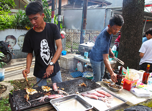 Bandung, West Java, Indonesia - December 11, 2016. Car Free Day is held every Sunday morning at the upper end of Jalan Buah Batu in the city of Bandung. People selling grilled squid.