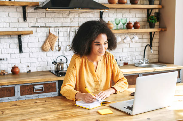 istock Beautiful afro girl writes in notebook from laptop 1286842786