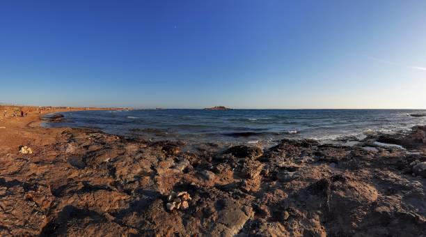 Portopalo di Capo Passero - Overview of the Island of Currents Portopalo di Capo Passero, Sicily, Italy - August 26, 2020: Panoramic photo of the Isola delle Correnti at sunset portopalo stock pictures, royalty-free photos & images