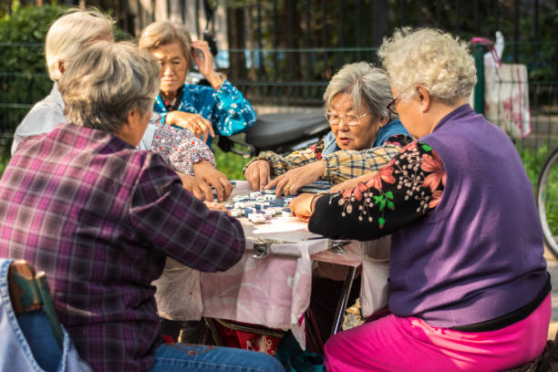 Elderly women playing Mahjong game in the street in Beijing, China Beijing / China - October 4, 2015: Elderly women playing Mahjong game in the street in Beijing, China prc stock pictures, royalty-free photos & images