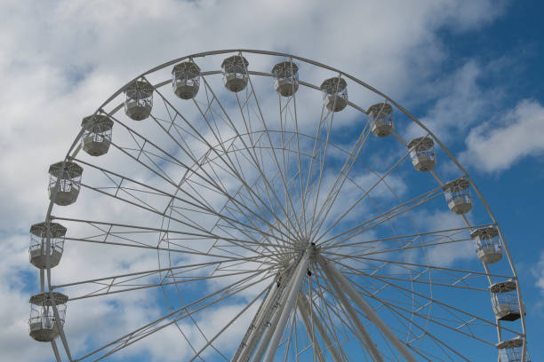istock Part of a white ferris wheel on a blue sky with clouds 1286847910