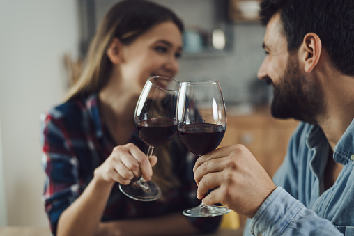 Close up of young couple toasting with wine at home
