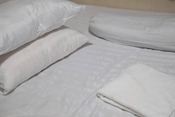 istock Close-up white bedding sheets and pillow with white towel. Fresh bed concept 1286854256