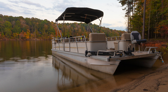 Pontoon boat beached on the shore of Falls Lake in Autumn