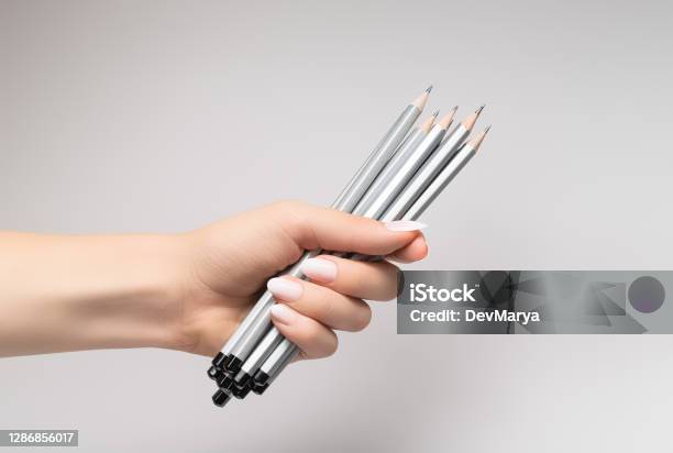 Female Hand With White Nail Design White Nail Polish Manicure Female Hand Hold Pack Of Pencils On Grey Background Stock Photo - Download Image Now