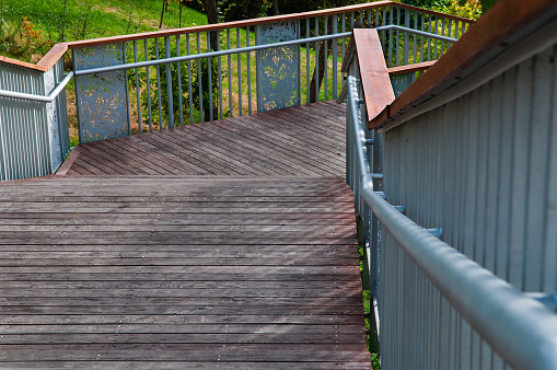 Modern wooden staircase with metal railings in a public park.