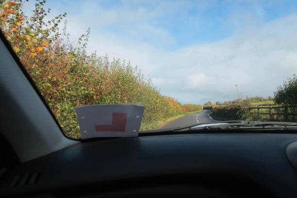 istock Image of passenger view through car windscreen with L Plate, driving on countryside road lined by hedges 1286859410