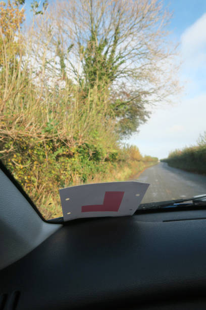 istock Image of passenger view through car windscreen with L Plate, driving on countryside road lined by hedges 1286859419