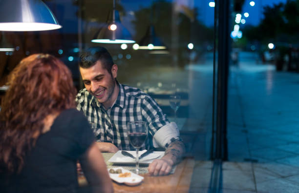 istock Young couple in modern restaurant having dinner. Smiling man behind the window in valentines date. 1286860755