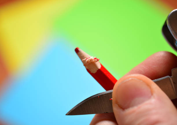 istock a man sharpens a colored pencil with a pocket knife. copy space. 1286860855