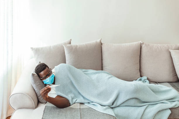 istock Ill man covered with blanket holding thermometer 1286862220