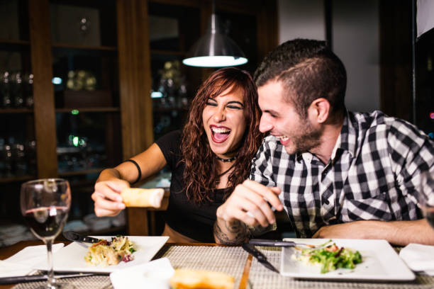 istock Young modern couple in restaurant drinking wine with ambient light, laughing in suceesful date 1286862311